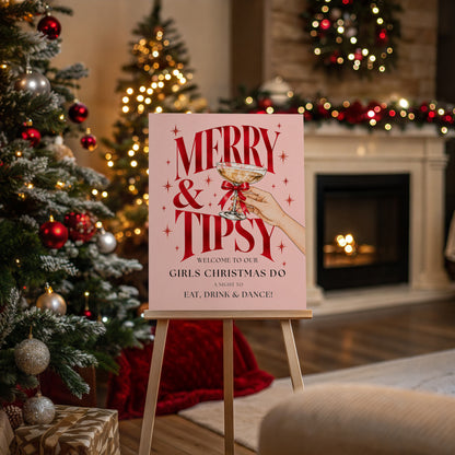 Pink Merry & Tipsy Christmas party welcome sign displayed on a wooden easel